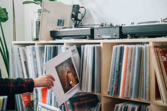 Person in flannel placing a vinyl record onto a shelf