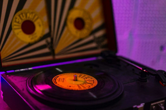 Vinyl record being played on a record player with purple lighting in background