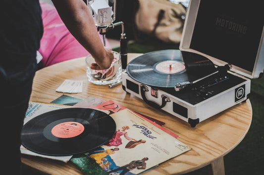 person near vinyl record player on brown surface