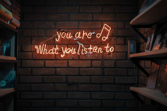 Brick wall with neon sign that says ‘you are what you listen to’