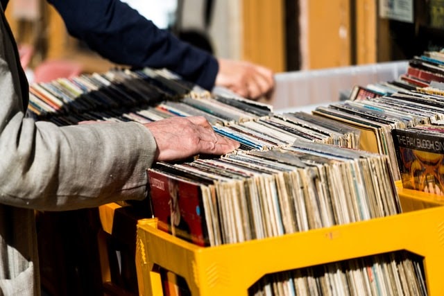Hand browsing a container of vinyl records