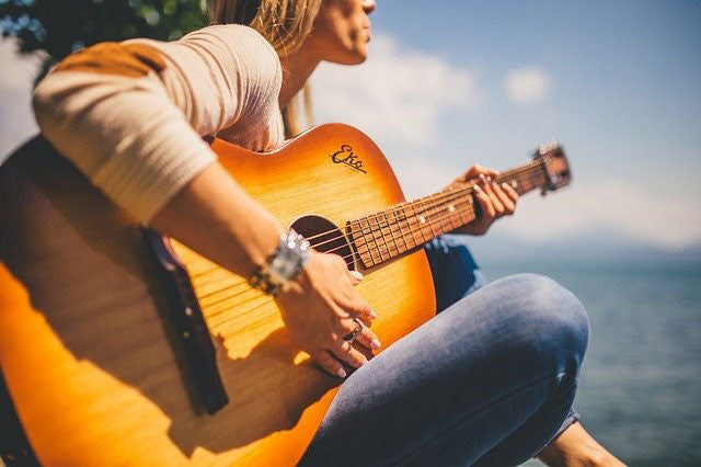 woman playing guitar outdoors beneath the summer sun
