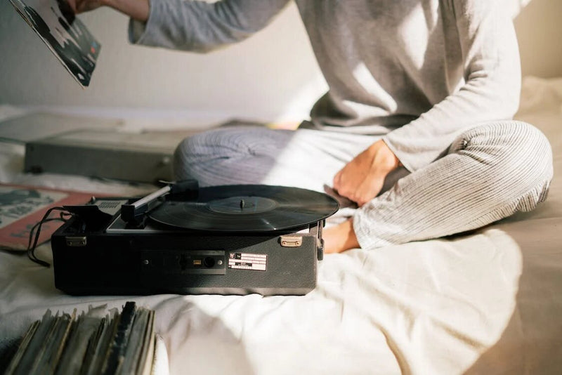 A person sitting on a bed and playing vinyl records