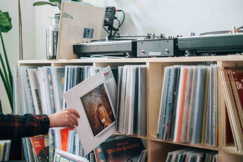 Person in flannel placing a vinyl record onto a shelf