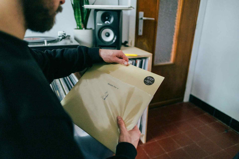 Man pulling a vinyl record out of a sleeve in front of a record collection