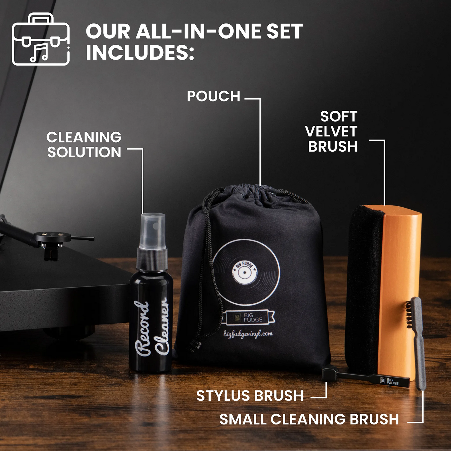 A record cleaning kit displayed on a wooden surface against a dark background, including a black cleaning solution bottle labeled 'Record Cleaner,' a black drawstring pouch with a vinyl record graphic, a soft velvet brush, a rectangular orange-and-black cleaning block, and two small brushes. Text at the top reads 'OUR ALL-IN-ONE SET INCLUDES:' with callouts naming each included item.