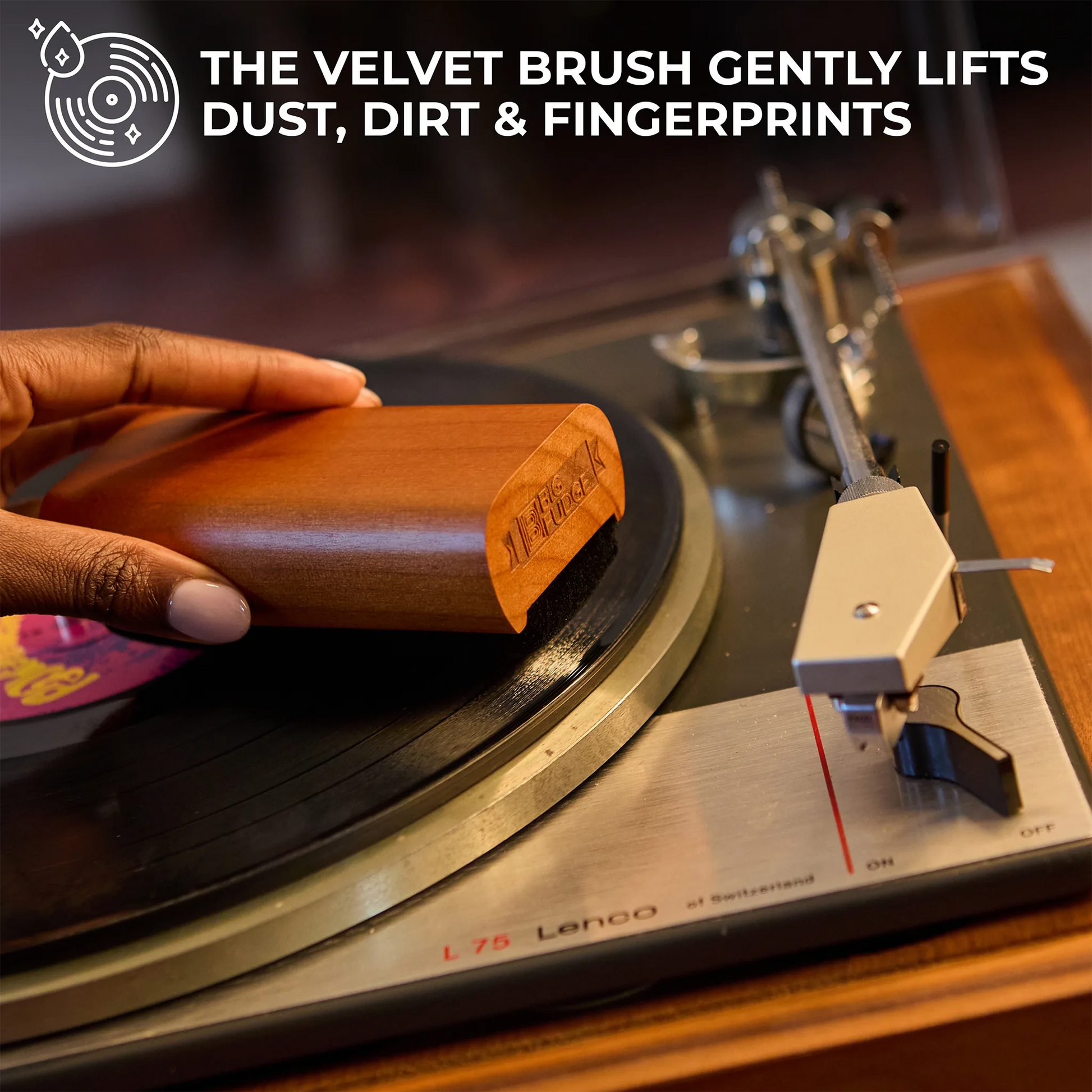 Person cleaning a vinyl record with a velvet brush on a turntable.