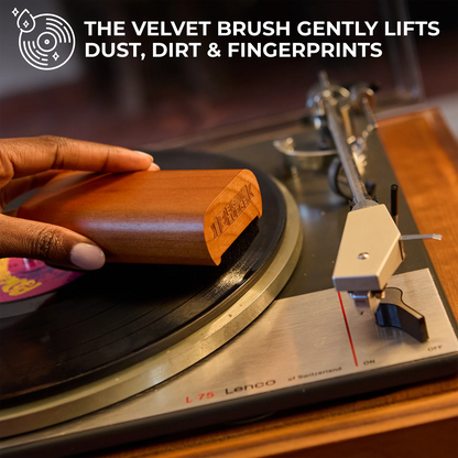 Person cleaning a vinyl record with a velvet brush on a turntable.