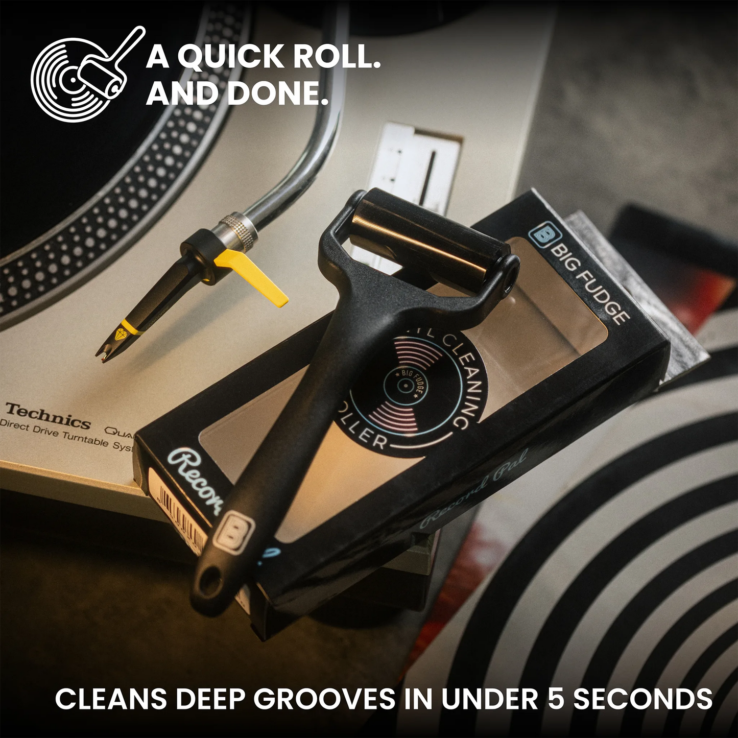 A black vinyl record cleaning brush with a yellow lever and black handle is shown resting on its retail box, alongside a turntable needle and promotional text about quick groove cleaning.