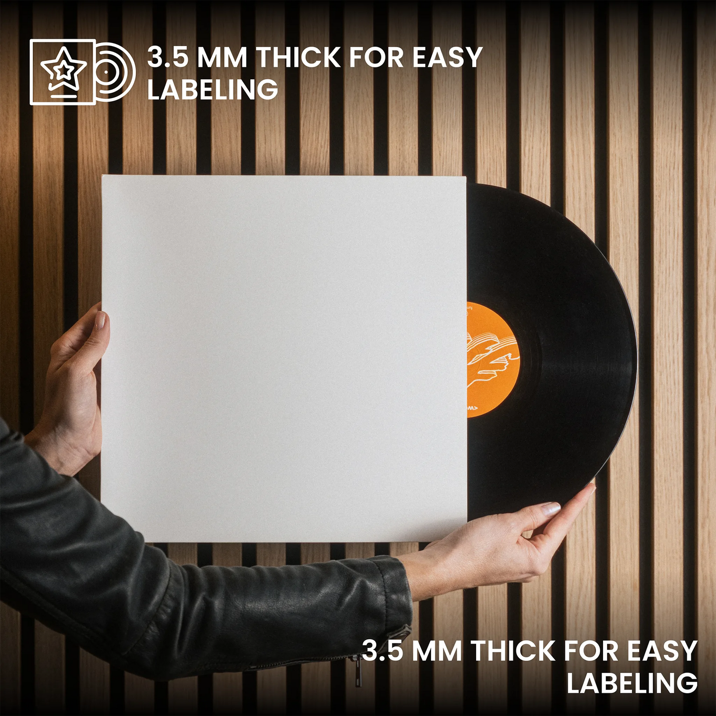 A person in a black leather jacket holds a blank white vinyl record sleeve in front of a black vinyl record, with text reading '3.5 MM THICK FOR EASY LABELING' on a wood slat background. _Glossy White