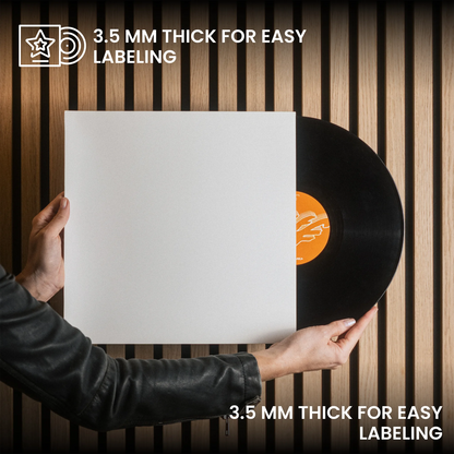 A person in a black leather jacket holds a blank white vinyl record sleeve in front of a black vinyl record, with text reading '3.5 MM THICK FOR EASY LABELING' on a wood slat background. _Glossy White