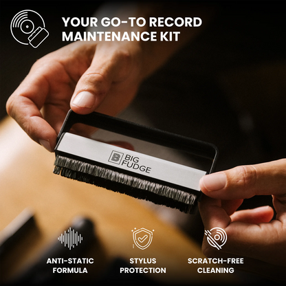 A close-up of a person holding a record cleaning brush labeled BIG FUDGE, with marketing text reading 'YOUR GO-TO RECORD MAINTENANCE KIT' and feature icons for anti-static formula, stylus protection, and scratch-free cleaning.