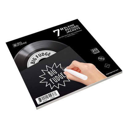 A boxed set of Big Fudge blank record jackets shown at an angle on a white background. The packaging is black with a vinyl record graphic, white text, and an illustration of a hand holding a marker writing on the front cover. _Matte Black _7 inch
