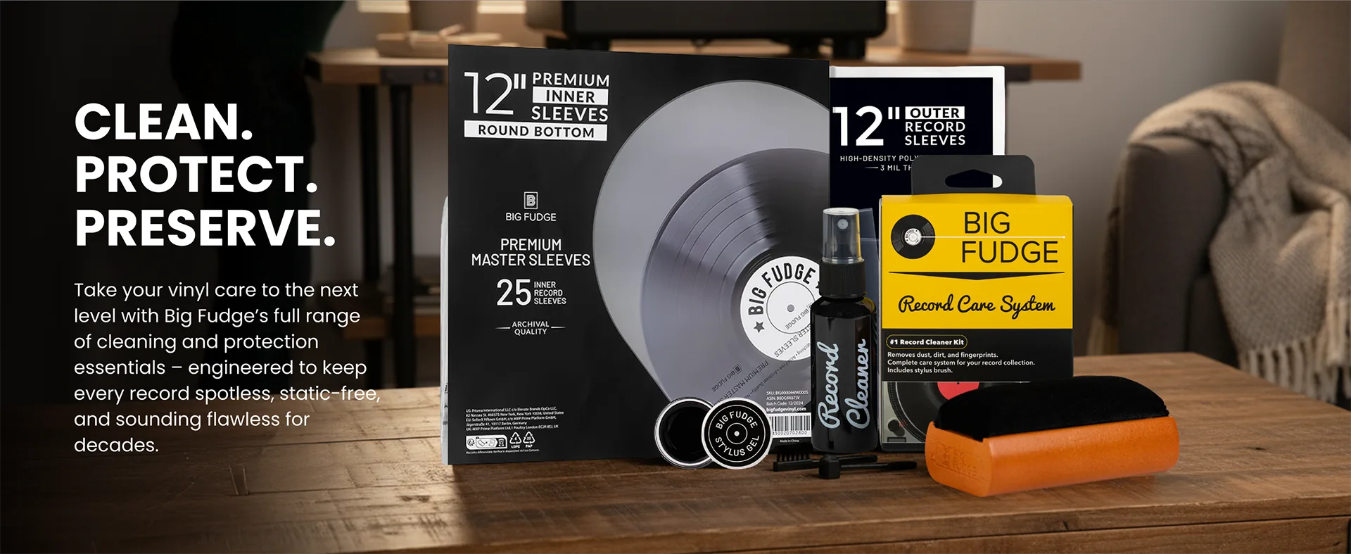Vinyl record care and preservation kit displayed on a wooden table, including a black box, a gray vinyl record, a black bottle, a yellow Big Fudge record care sleeve, and an orange cleaning block, with promotional text on the left.